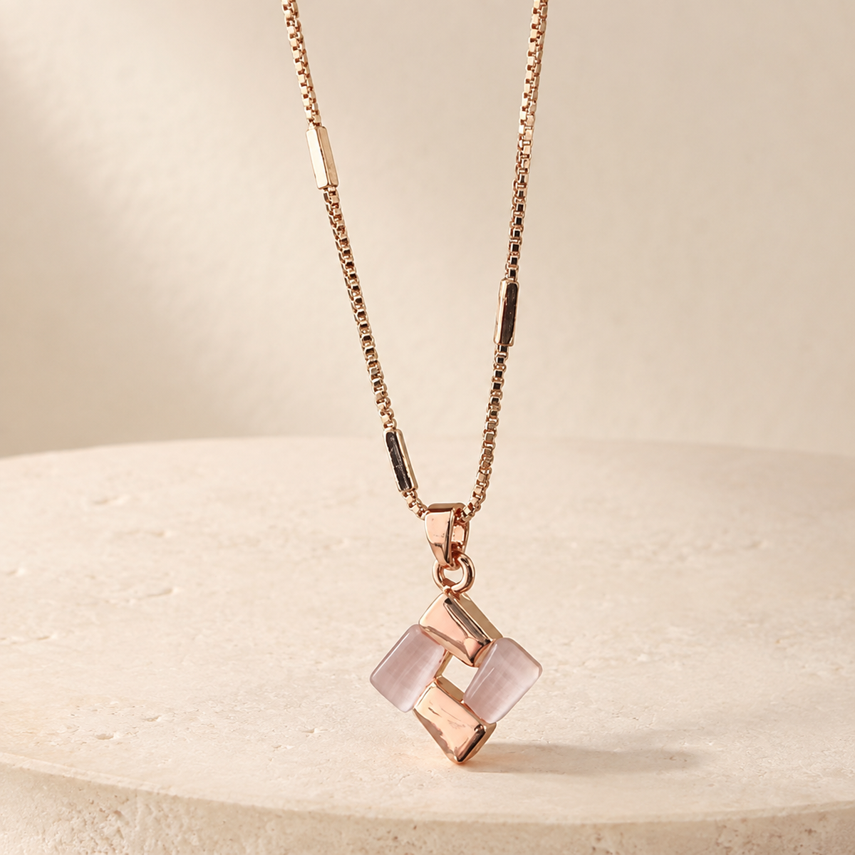 Rosé Geometric Pendant Necklace on a warm ivory studio background
